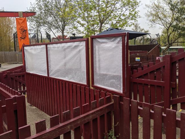 An example of the queue line barriers in the queue for Dragon's Fury at Chessington World of Adventures. The barriers are in the form of temporary plastic sheeting stretched across wooden frames.